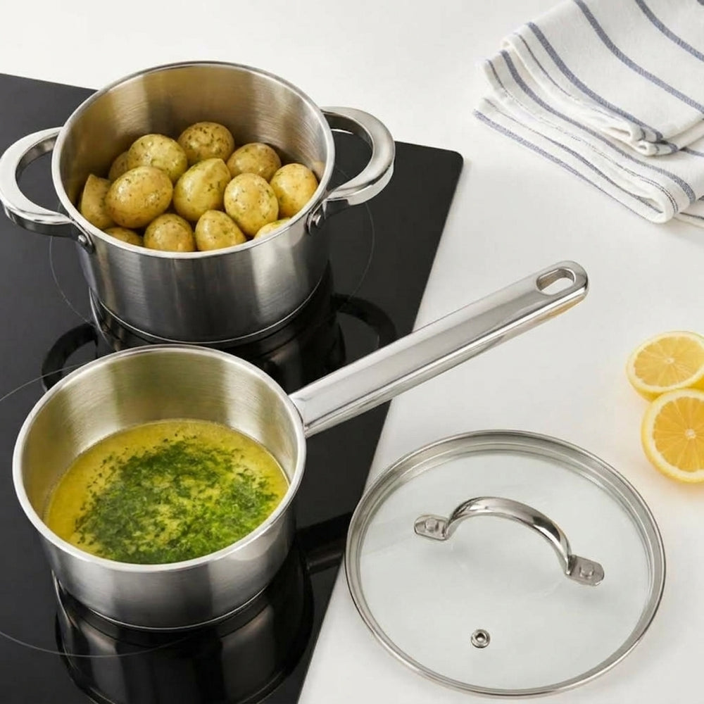 Cooking RVS kookpan met aardappels en steelpan met kruidenboter op inductie, van bovenaf
