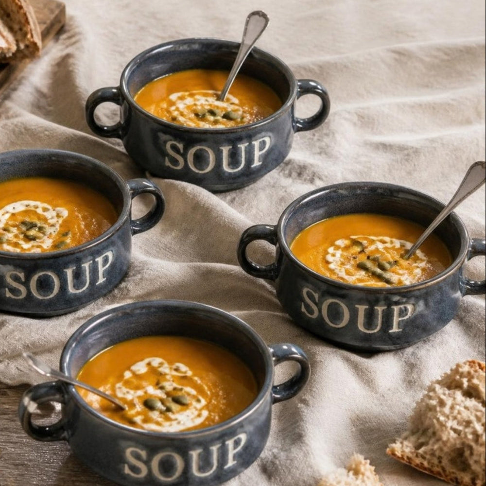 Vier blauwe Soup soepkommen met pompoensoep op een gedekte tafel, van bovenaf