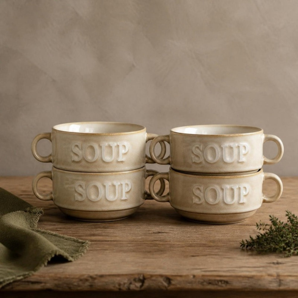 Vier crème Soup soepkommen gestapeld in twee stapels op een eiken tafel