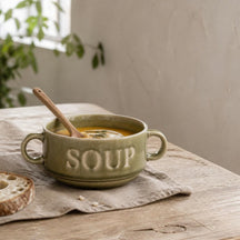 Groene Soup soepkom met pompoensoep en houten lepel op een linnen servet