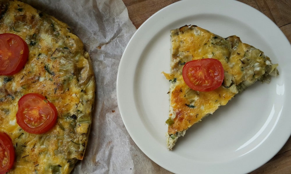 Una esponjosa tortilla italiana con calabacín, corazones de alcachofa y hierbas frescas