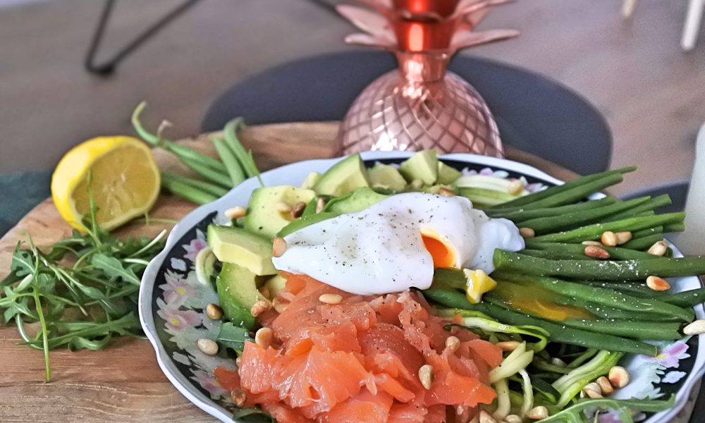 Un bowl fresco y nutritivo con espirales de calabacín, salmón ahumado y un huevo pochado