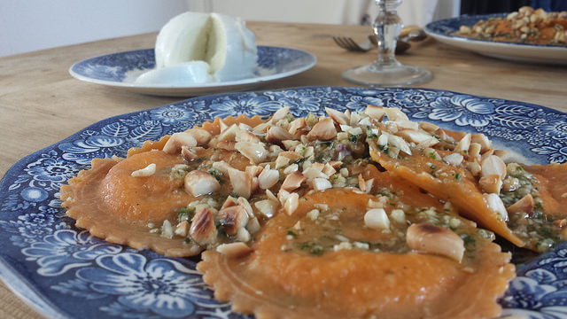 Puré cremoso de berenjena con ravioli relleno, pesto y almendras crujientes