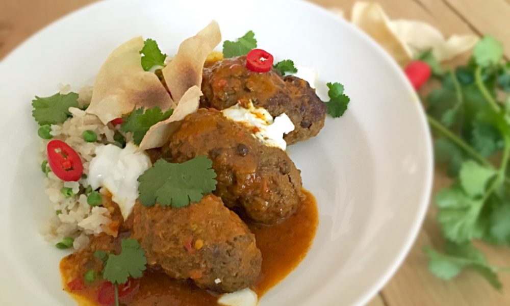 Albóndigas jugosas en una cremosa salsa de coco y curry con arroz aromático